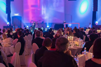 Corporate Event Production Rentals Attendees sitting around circular tables at a banquet