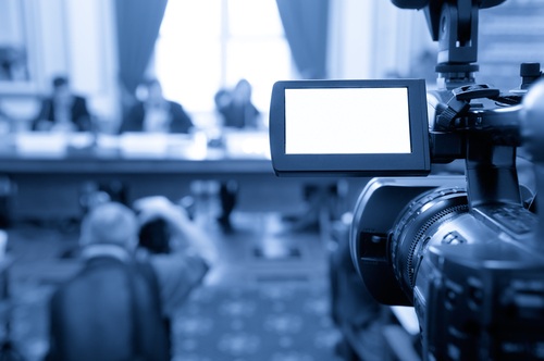 Public Relations Rentals A production camera with viewfinder visable, pointing at speakers at a table