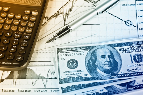 Accounting Rentals A calculator, pen, and American currency laying on top of financial charts