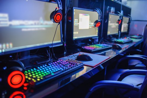 Gaming Rentals A row of gaming desktops, monitors, mice, chairs, and gaming headsets powered on and boasting LED RGB lighting