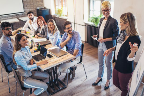 Experienced Agents in All Industries A group of employees around a small conference table watching a presentation being given