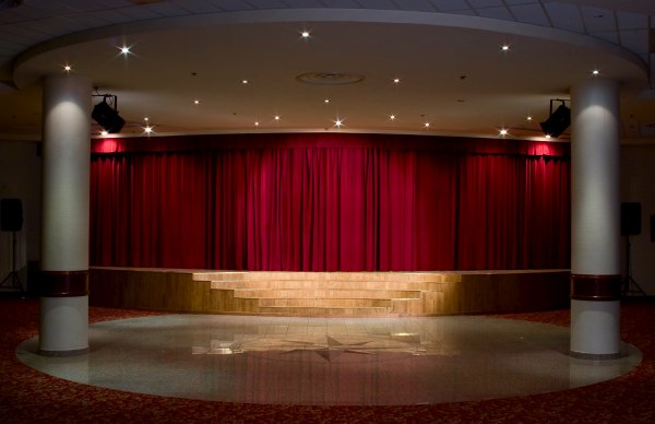 Affordable Pipe and Drape Rentals An empty, well lit stage with red drape behind it