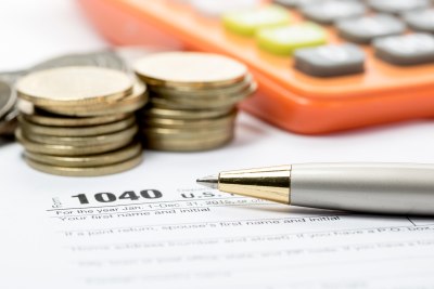 Tax Season Technology Rentals An IRS 1040 form with a pen and quarters on top of it